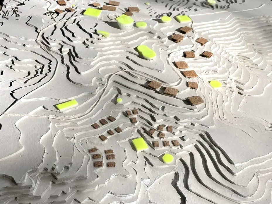 A white terrain model with lime and cork blocks marking where things go on the slopes
